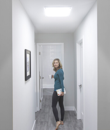 Woman walking in a hallway lit by solatube.