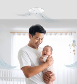 A father holding his baby beneath a whole house fan