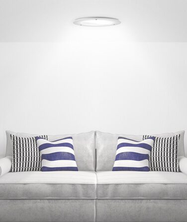 A couch with striped pillows beneath a solatube skylight