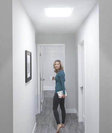 A woman in a hallway underneath a solatube skylight